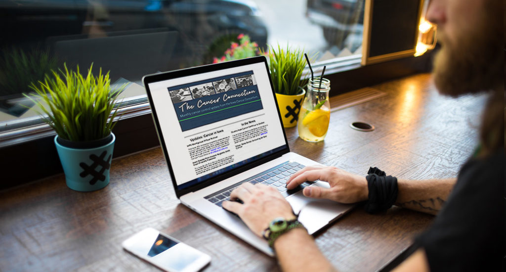 Man reading the Iowa Cancer Connection Newsletter on a laptop