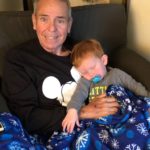 Man holding his grandson, cuddling under a blanket