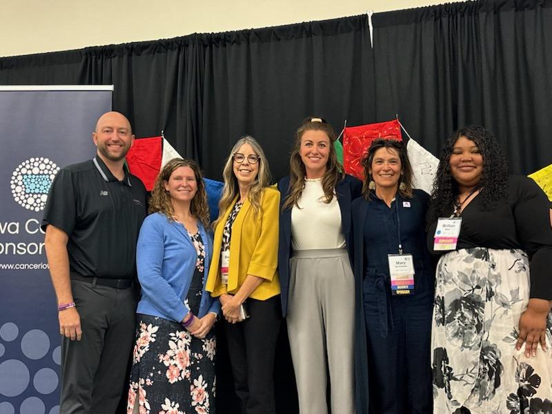 6 survivorship panelists stand together for a photo.